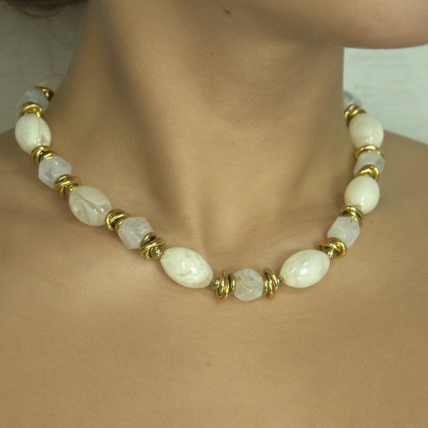 Necklace with white beads and gold accents worn by a person