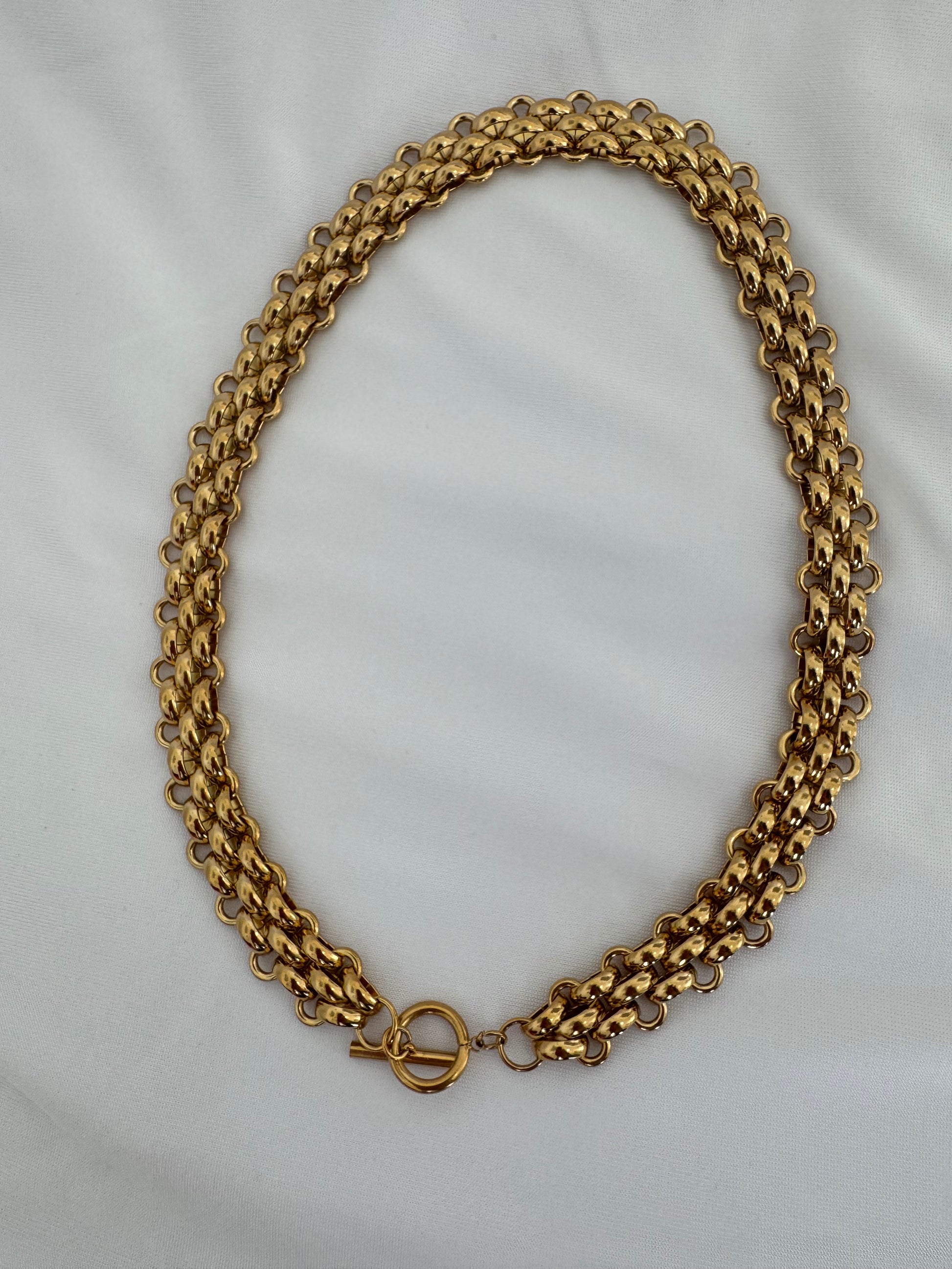 Gold chain necklace on a light gray background