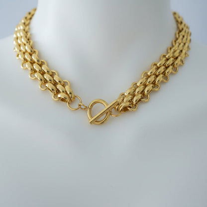 Gold Braided Necklace - close-up detail of braided chain texture
Gold chain necklace on a person's neck with a blurred background