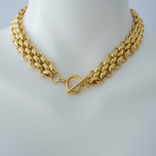 Gold Braided Necklace - close-up detail of braided chain texture
Gold chain necklace on a person's neck with a blurred background