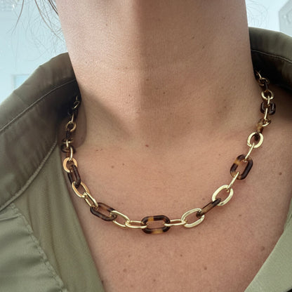 Gold chain bracelet on a wrist with a neutral background