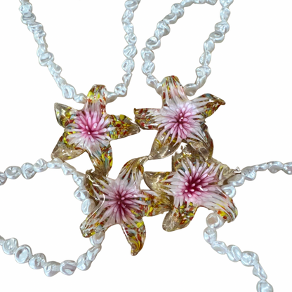 Necklace with floral pendant on a white background.
Pearl Star Necklace with imitation pearls and star pendant in resin chain Front view on white background
