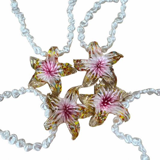 Necklace with floral pendant on a white background.
Pearl Star Necklace with imitation pearls and star pendant in resin chain Front view on white background
